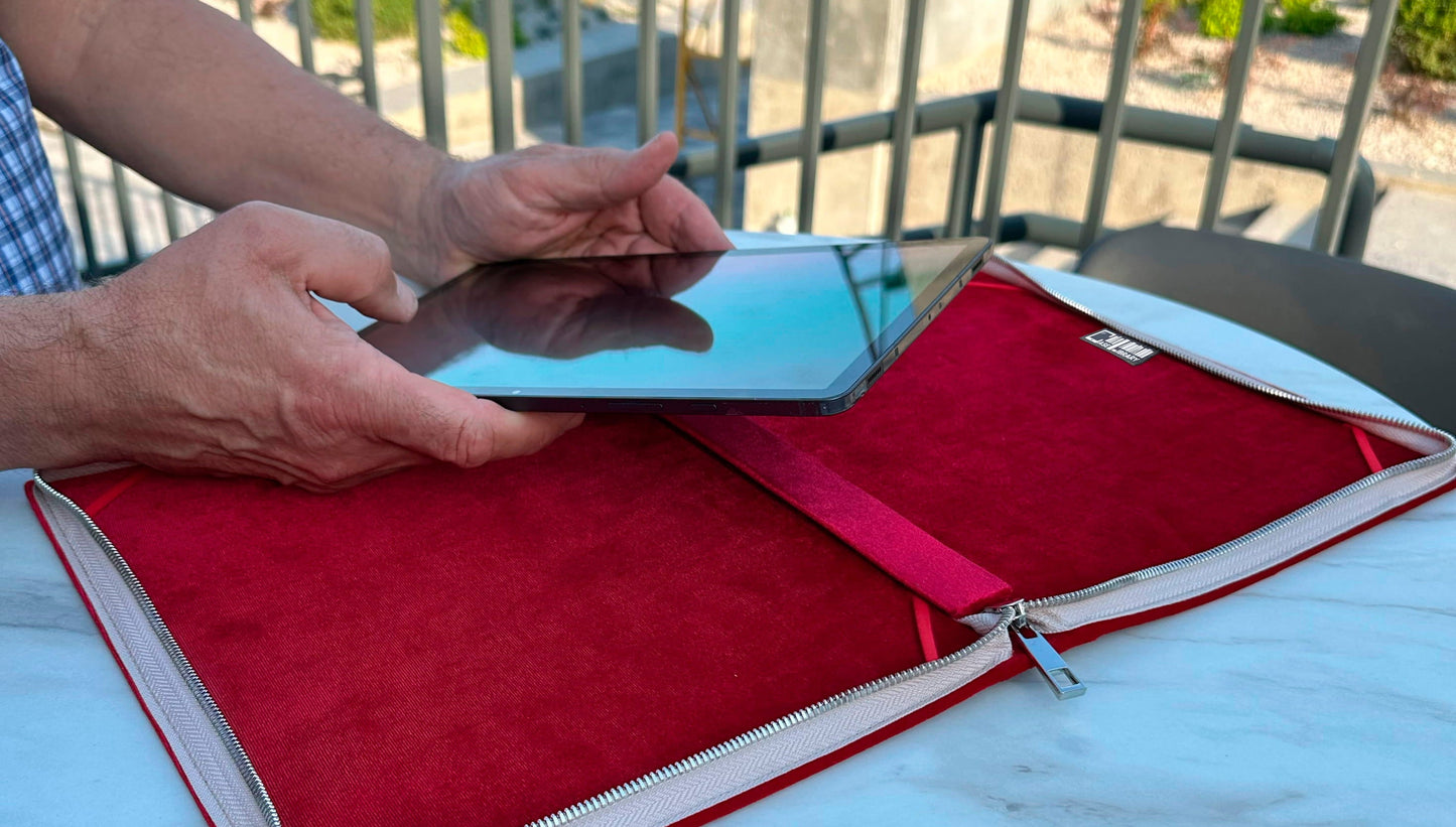 Hands placing a Supernote A5 X2 Manta e-ink into a red velvet-lined zippered folio case on a round outdoor table, with a pen resting inside the case for writing use.